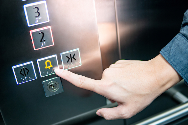 Liftmanagement mit LiftPLAN360: Eine Person drückt den Notrufknopf in einemmAufzug.