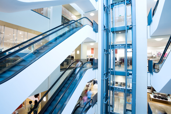 Aufzugsverwaltung mit LiftPLAN360: Mehrere Rolltreppen und ein Fahrstuhl in einem Einkaufszentrum.